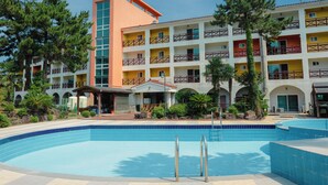 Ein Hotel mit Schwimmbad, mehreren Balkonen und einem zentralen Turm.