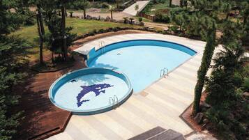 A swimming pool with a dolphin design, surrounded by trees and a wooden deck.