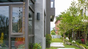 A modern building with large windows, a wooden deck, and a garden with stepping stones. - Sunny Stream Villa (Wujie)