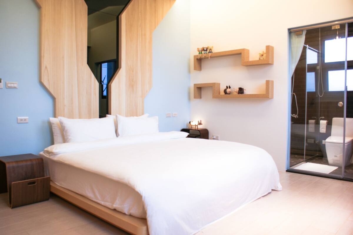 Un dormitorio moderno con una cama grande, cabecera de madera, mesitas de noche y estantes empotrados con adornos.