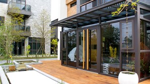A modern building with a wooden deck, glass doors, and a large white planter. - Sunny Stream Villa (Wujie)