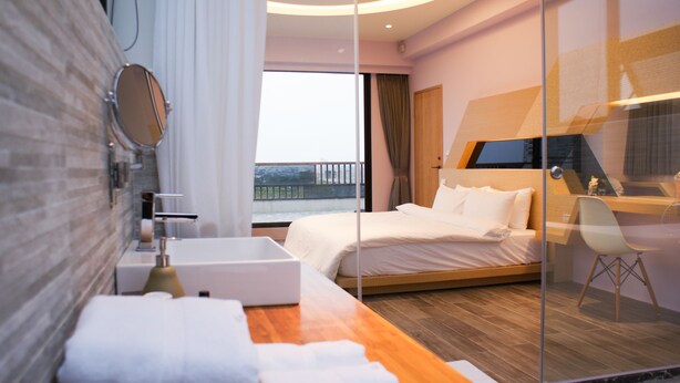 A modern hotel room with a bed, a desk, a chair, a mirror, and a view of the outside. - Sunny Stream Villa (Wujie)