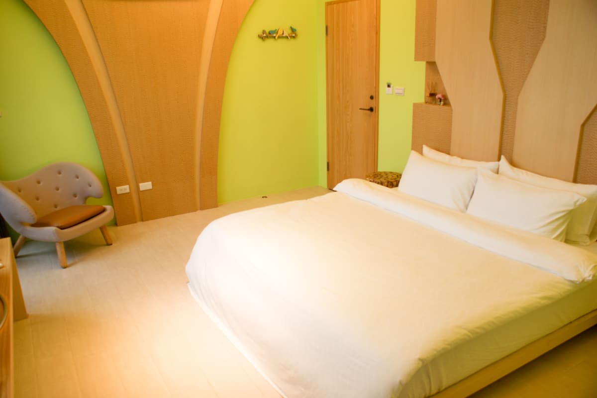 Un dormitorio con una cama, una silla y un armario de madera.