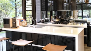 A modern kitchen with a large island, bar stools, and hanging pendant lights. - Sunny Stream Villa (Wujie)