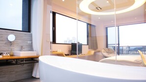 A modern hotel room with a curved bed, a large window, a vanity with a mirror, and a city view. - Sunny Stream Villa (Wujie)