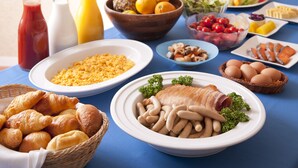 A breakfast buffet with various dishes including eggs, pastries, and fruits.