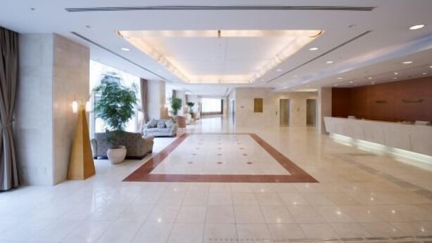 A spacious lobby with a central seating area, a reception desk, and a large window providing natural light.