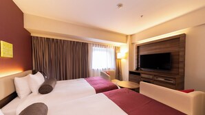 Habitación de hotel con dos camas, televisión, escritorio y una silla.