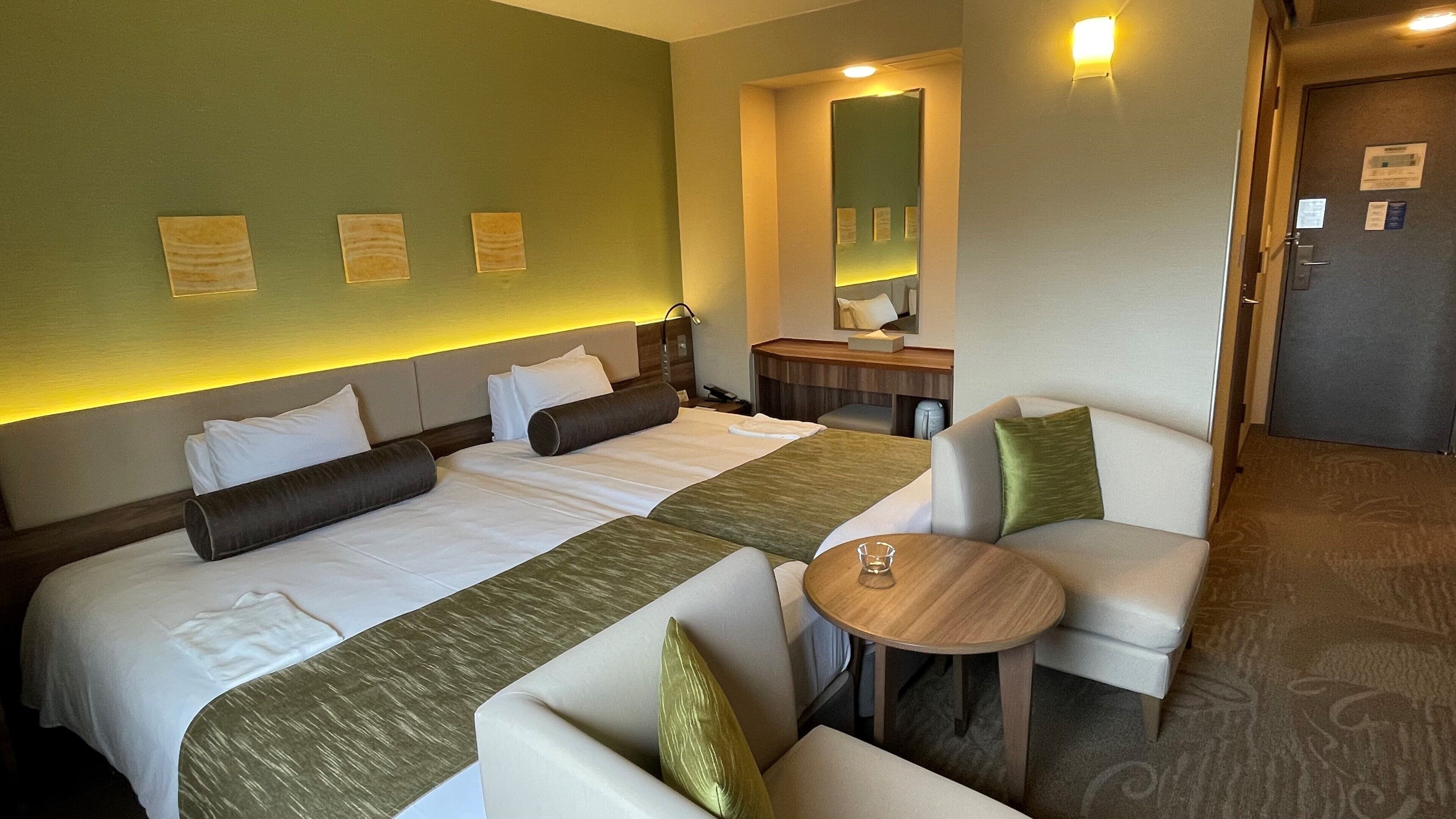 Una habitaci ón de hotel con una cama grande, dos mesitas de noche, una pequeña mesa redonda y un sofá.