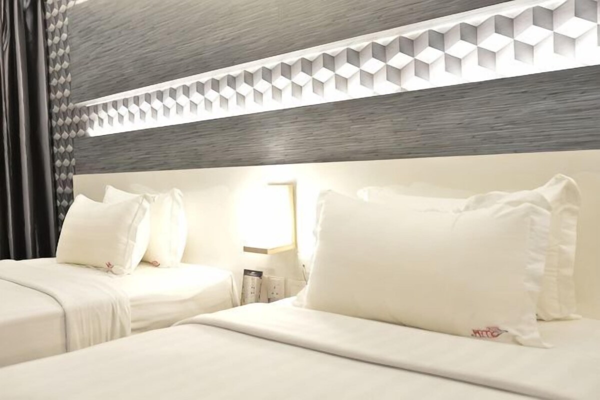 A hotel room with two beds, a wooden headboard, and a geometric light fixture.