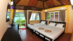 A room with two beds, a desk, and a view of the sea.