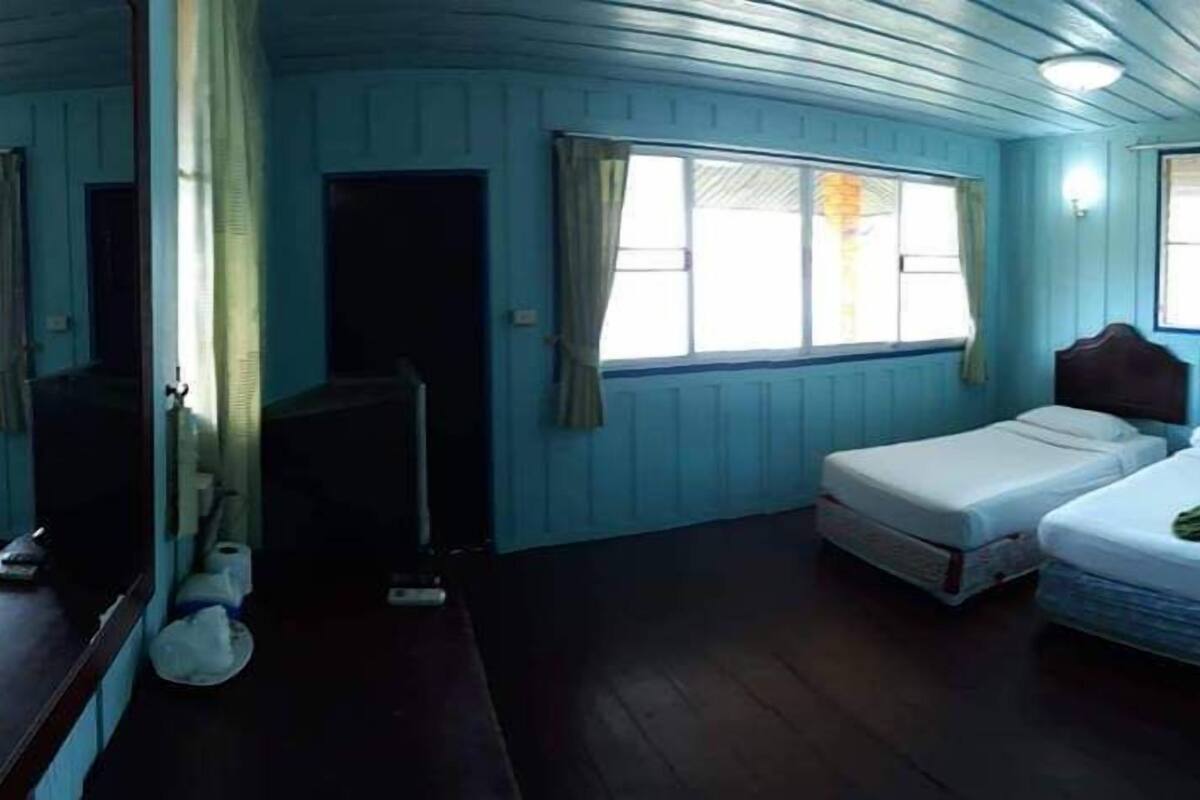 A room with two beds, a window with curtains, a mirror, and a ceiling fan.