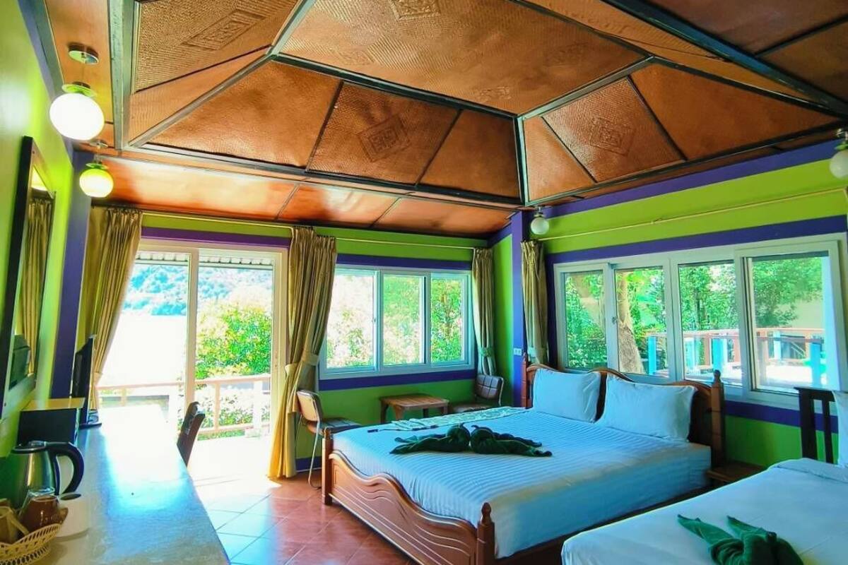 A room with two beds, a large window, and a ceiling with a geometric pattern.