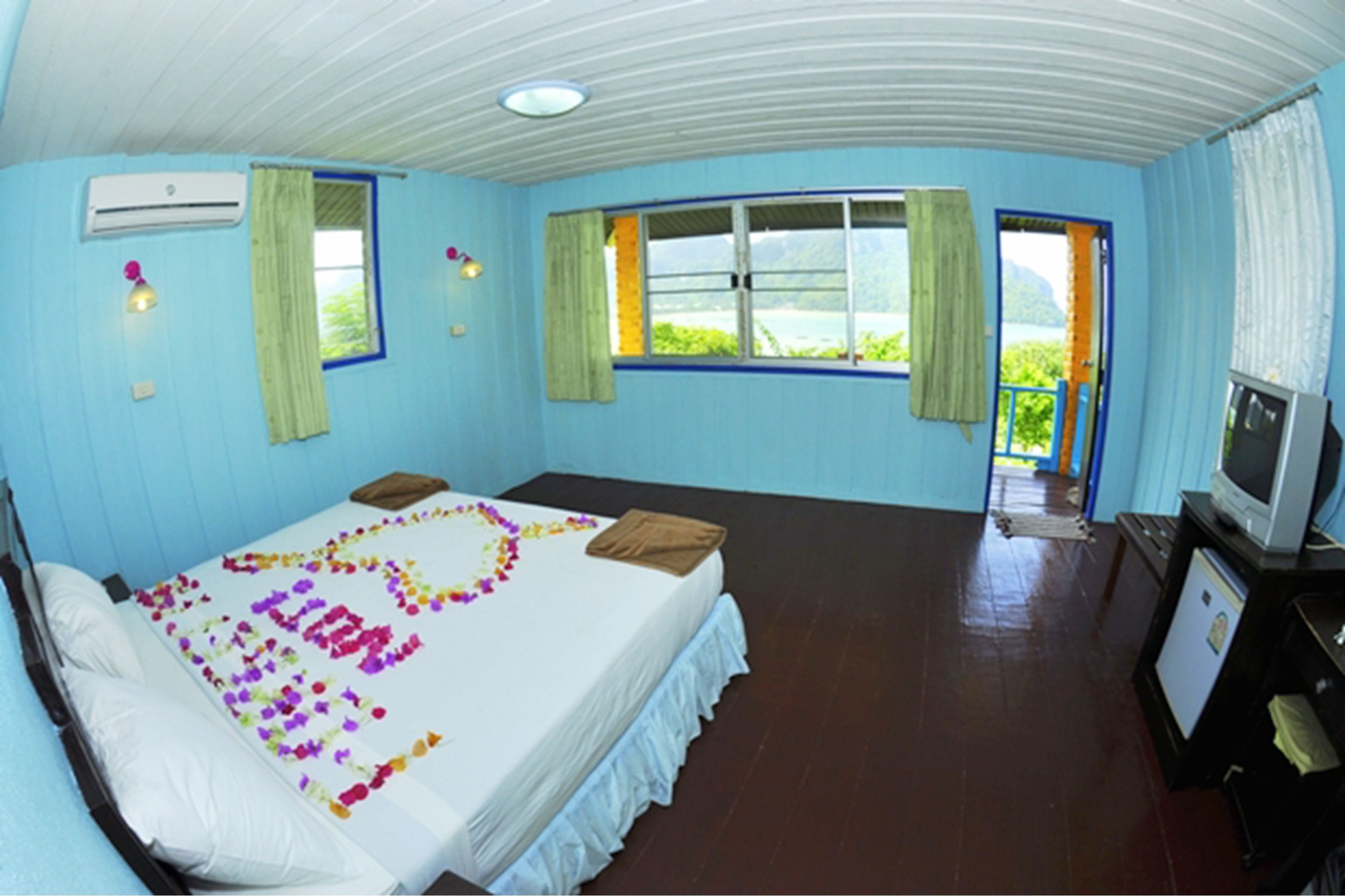 A room with a bed, a television, and a window with curtains.