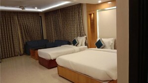 Quarto de hotel com duas camas de solteiro, um sofá e um ventilador de teto.