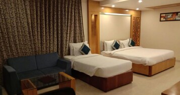A hotel room with two beds, a sofa, a small table, and curtains.