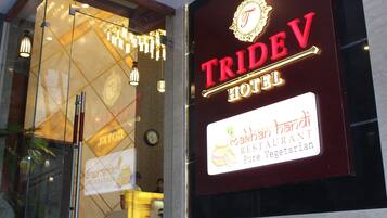 A TRIDEV HOTEL sign with a logo and a restaurant advertisement for "Makhani Handi Pure Vegetarian".