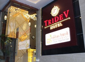 Letrero de TRIDEV HOTEL con un logotipo y un anuncio de restaurante para 'Makhani Handi Pure Vegetarian'.