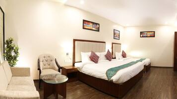 A hotel room with a large bed, a sofa, a chair, a small table, and a mirror.