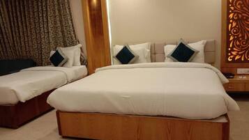 A hotel room with two beds, each with white bedding and dark pillows, a wooden headboard, and a decorative panel on the wall.