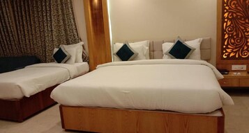 A hotel room with two beds, each with white bedding and dark pillows, a wooden headboard, and a decorative panel on the wall.