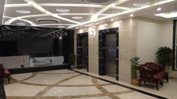 Um lobby moderno com piso de mármore, balcão de recepção e área de estar com cadeiras.