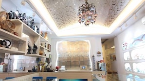 A modern interior with a glass dining table, blue chairs, and a chandelier. Shelves with various decorative items line the walls. - Zi Jing Fang lnn (Hengchun)