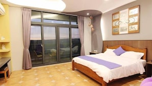 A bedroom with a large bed, a desk, and a view through a sliding glass door. - Zi Jing Fang lnn (Hengchun)