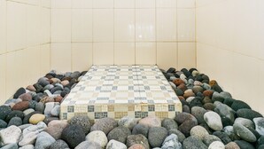 A shower area with a tiled floor, a showerhead, and a tiled wall.