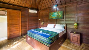 A wooden room with a bed, a painting, and a nightstand.