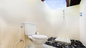 A bathroom with a toilet, a shower, and a tiled floor with a pebble pattern.