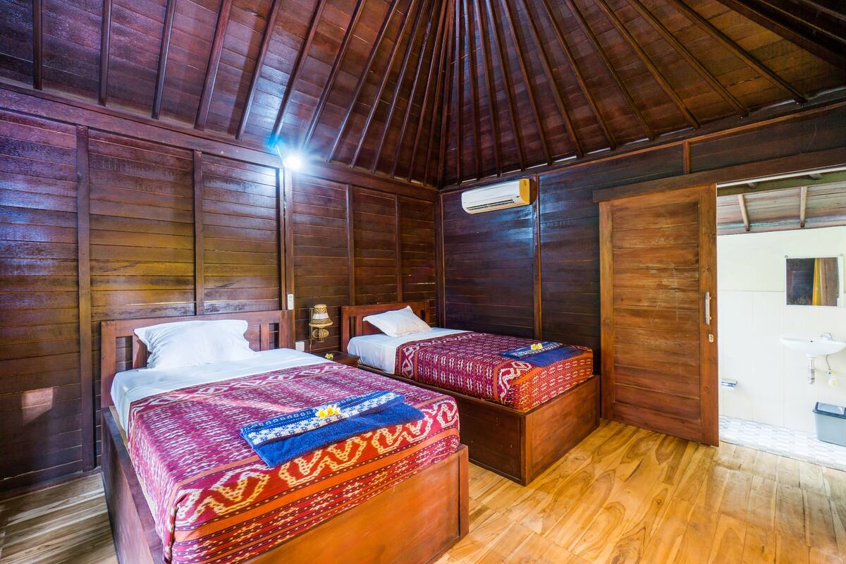 Een houten kamer met twee bedden, een kledingkast en een badkamer.