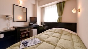 Habitación de hotel con cama, escritorio, computadora, teléfono y espejo.