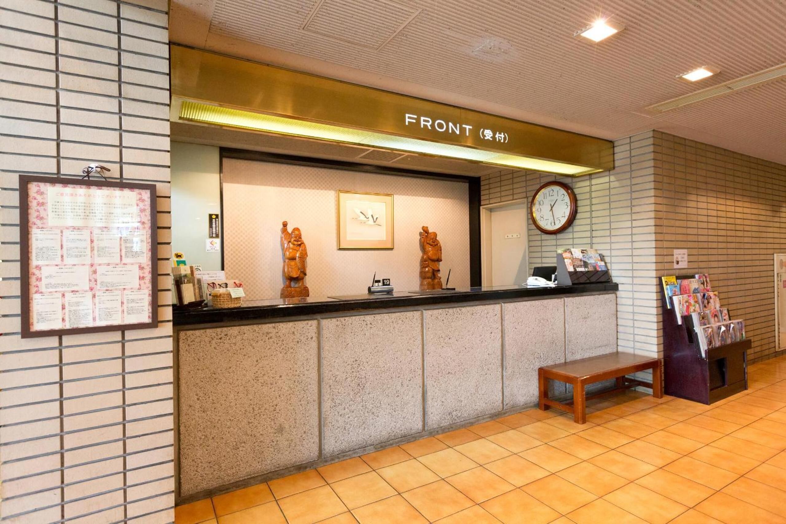 Un espace d’accueil avec un comptoir, une horloge et un banc.