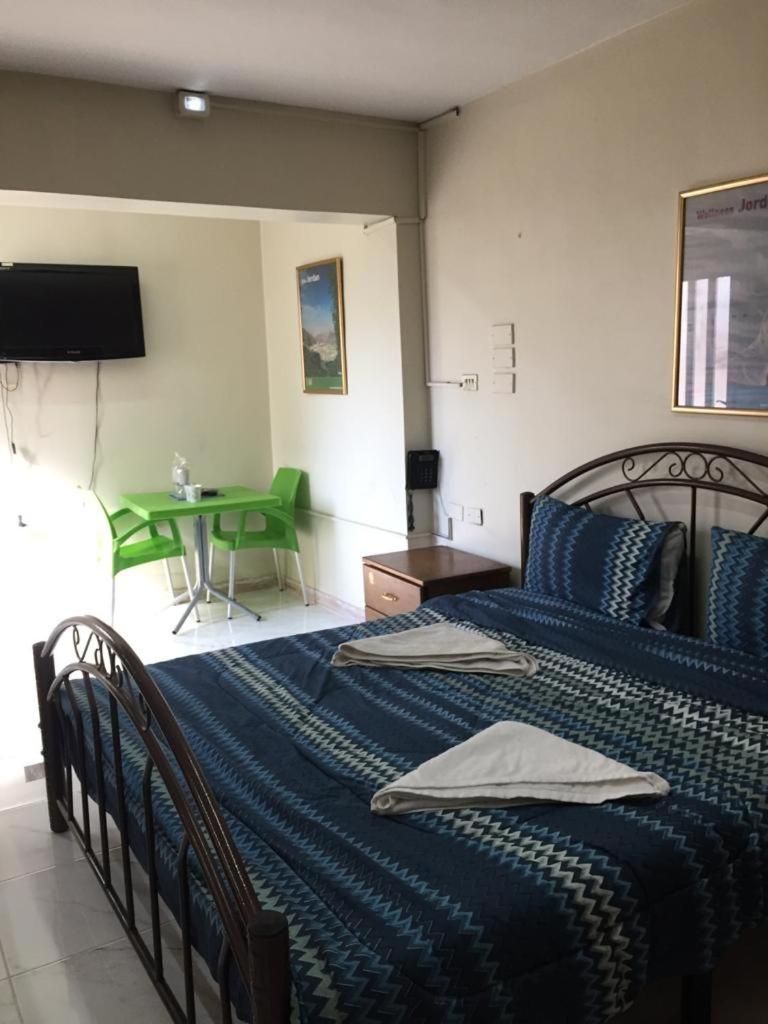 Een slaapkamer met een bed, een bureau, een stoel, een televisie en een schilderij aan de muur.