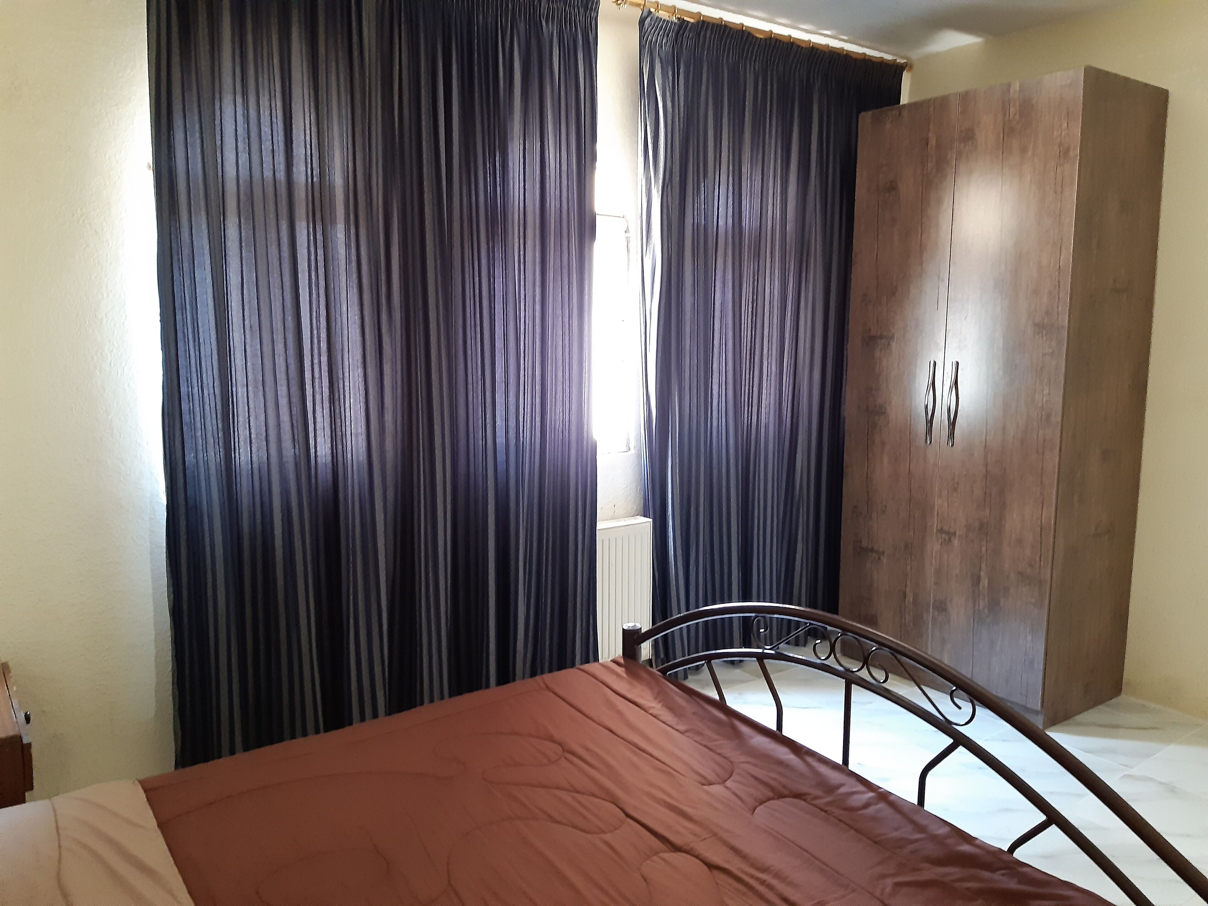 Un dormitorio con cama, armario y cortinas.