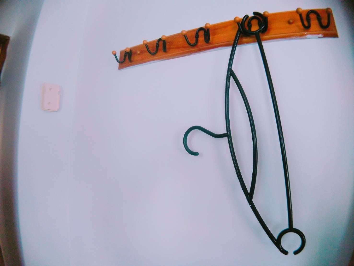 A wooden coat rack with hooks against a plain wall.