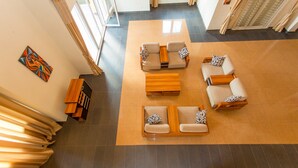 Un hall d’entrée spacieux avec un grand espace salon, une table basse en bois et un téléviseur fixé au mur.