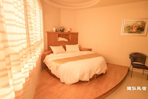A bedroom with a bed, a wooden headboard, a nightstand, a chair, and a painting on the wall. - Long Hong B&B (Magong)