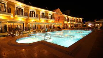 Ein Hotel mit Schwimmbad, Außenbereich und einer gut beleuchteten Fassade bei Nacht.