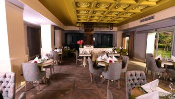 Un espace repas comprenant plusieurs tables et chaises, un plafond décoratif et une vue sur l’extérieur.