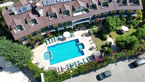 Vista aérea de un hotel con varios balcones, piscina y exuberante jardinería.