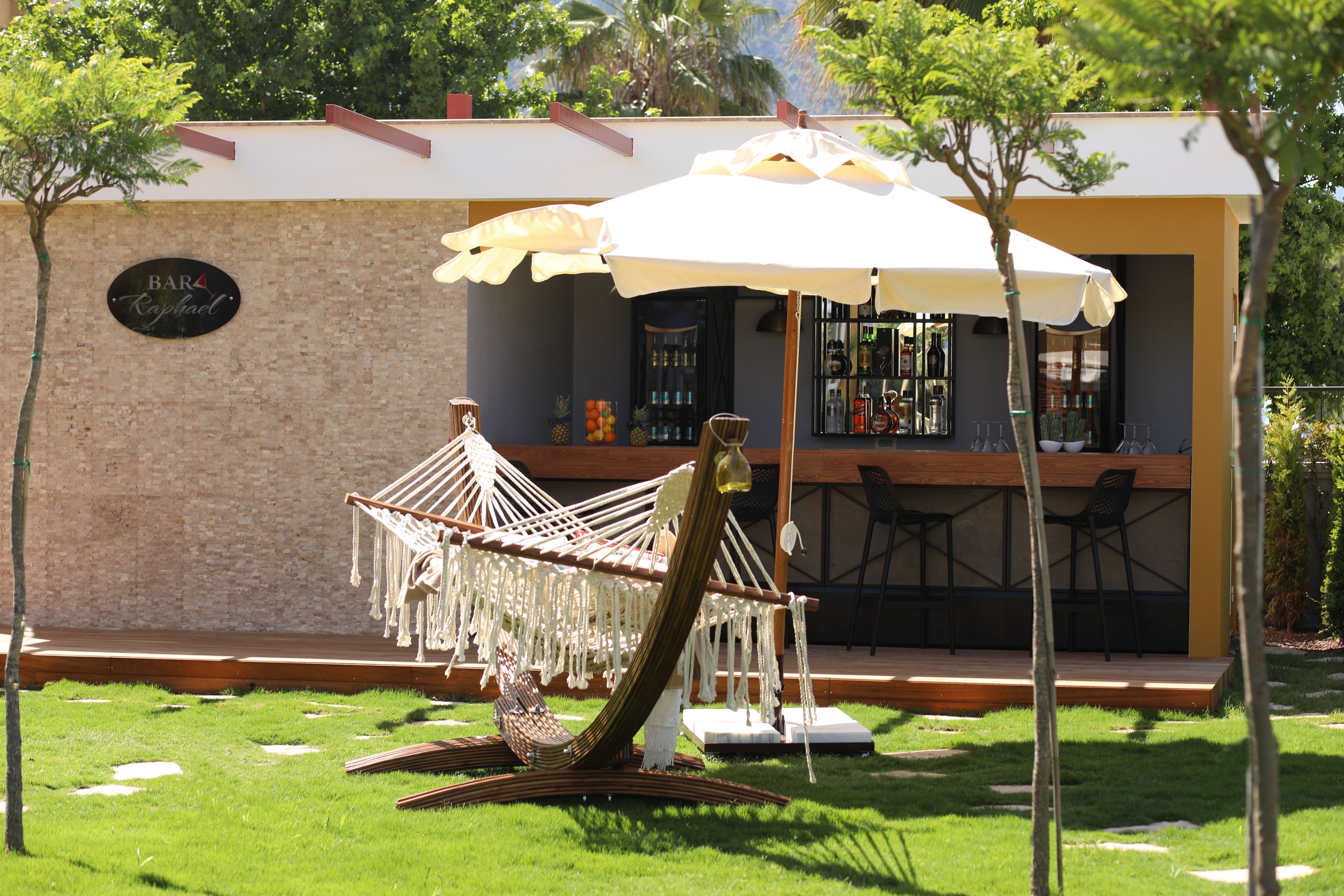 Una silla hamaca con dosel, un área de bar con sillas y un letrero que dice "BAR Kraphael".