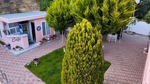 A cafe with a pink exterior, a small outdoor seating area, and a well-maintained lawn. - Ali Baba Butik Otel (Marmara)