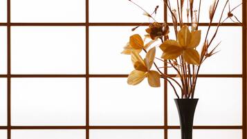 A vase with dried plants and flowers against a grid-patterned background.