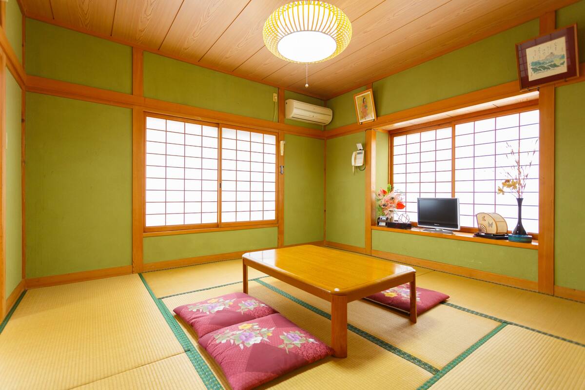A traditional Japanese room with tatami flooring, a low wooden table, and sliding shoji doors.