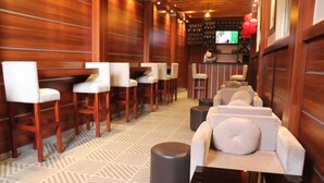 A bar area with wooden walls, white cushioned chairs, and a patterned floor. - Guzara Hotel Addis (Addis Ababa)