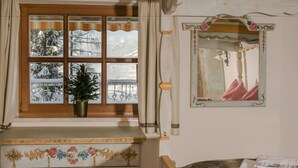 A room with a window, a small Christmas tree, and a mirror with a decorative frame. - Landhaus Alpenjuwel (Sankt Johann im Pongau)
