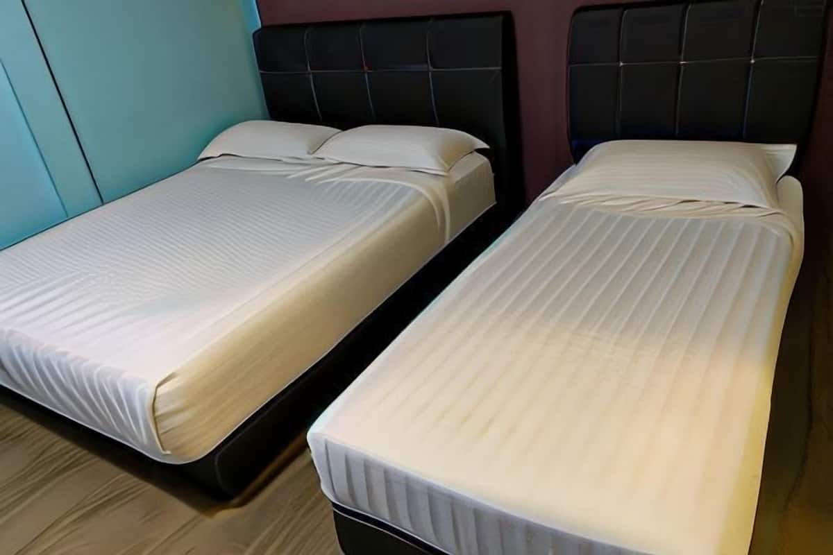 Two single beds with headboards, a wooden floor, and a teal wall.