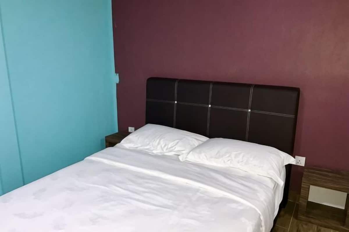 A bed with a headboard, a nightstand, and a wall with a teal door.